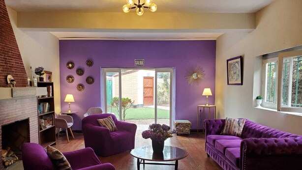 A living room with purple sofas, a fireplace, and a view of the outside. - Hostal The Place Miraflores (Lima)