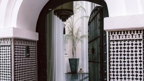 An arched doorway leading to a courtyard with a potted plant and a hanging light fixture.
