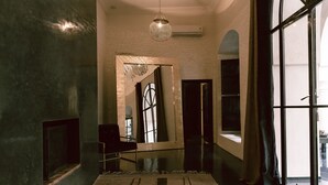 A modern interior with a large mirror reflecting a window, a hanging light fixture, and a patterned rug.
