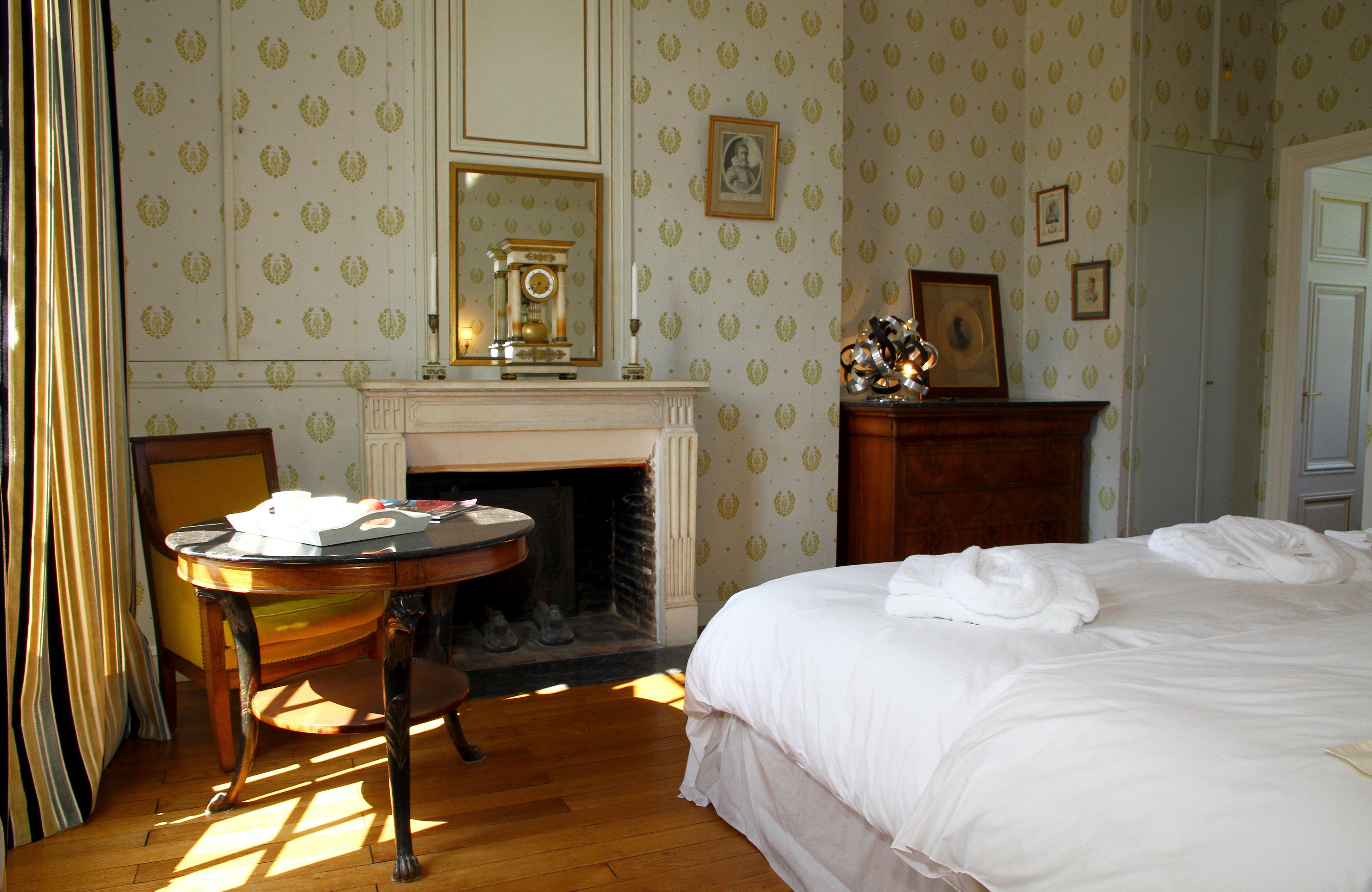 Een kamer met een bed, een open haard, een tafel en een spiegel.