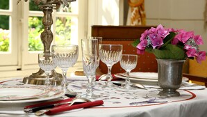 Una mesa dispuesta con copas de cristal, platos y cubiertos, un florero de plata con flores y un candelabro.