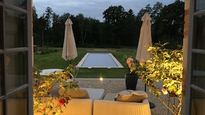Un espacio de estar al aire libre con mobiliario de mimbre, una piscina y sombrillas.