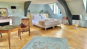 Un dormitorio con una cama, una silla, una mesa, una lámpara y un espejo.