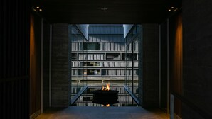 A modern interior with a central fire feature, a glass wall, and a metal railing. - Zaborin (Kutchan)
