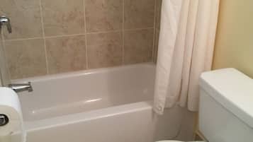 Un baño con bañera, inodoro y cortina de ducha.