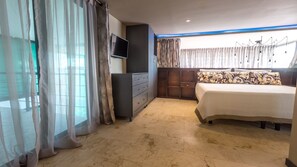 A bedroom with a bed, a TV mounted on the wall, a wardrobe, and a window with curtains.