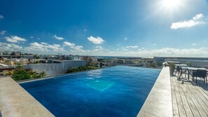 A rooftop infinity pool with a clear view of the ocean and cityscape.
