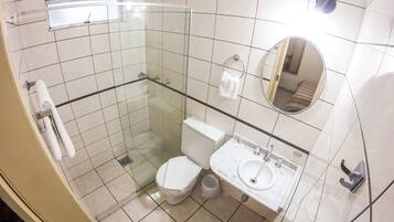 Un baño con cabina de ducha de vidrio, inodoro, lavabo y espejo.