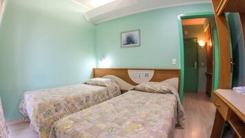 A room with two beds, a wooden headboard, a nightstand, and a painting on the wall.