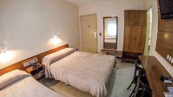 A hotel room with two beds, a desk, a chair, a TV, and a wardrobe.
