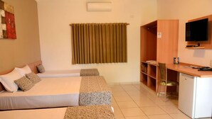 A hotel room with a bed, a desk, a television, and a wardrobe. - Pousada Vitalis (Olímpia)