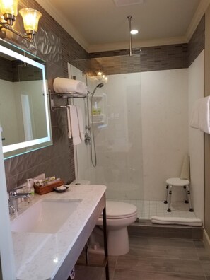 Un baño moderno con cabina de ducha de vidrio, inodoro blanco y tocador con encimera de mármol.