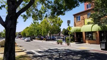 A street view with a pedestrian crossing, parked cars, and a building with a green awning.