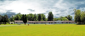 A motel with a large lawn, a covered parking area, and a row of single-story buildings with a flat roof. - Potsdam Inn (Potsdam)