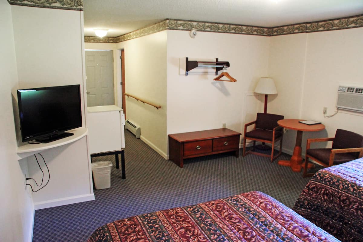 Une chambre d’hôtel équipée d’un lit, d’un bureau, d’une chaise, d’une télévision, d’une lampe et d’un porte-manteau.