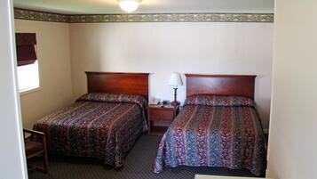 Une chambre d’hôtel avec deux lits simples, une table de chevet avec une lampe, un téléphone et une chaise.