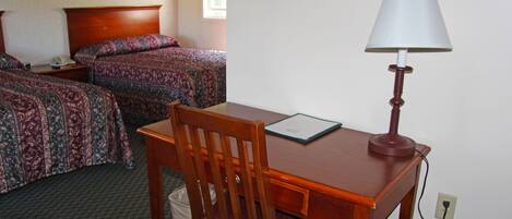 Une chambre d’hôtel avec deux lits, un bureau avec une lampe et une chaise.