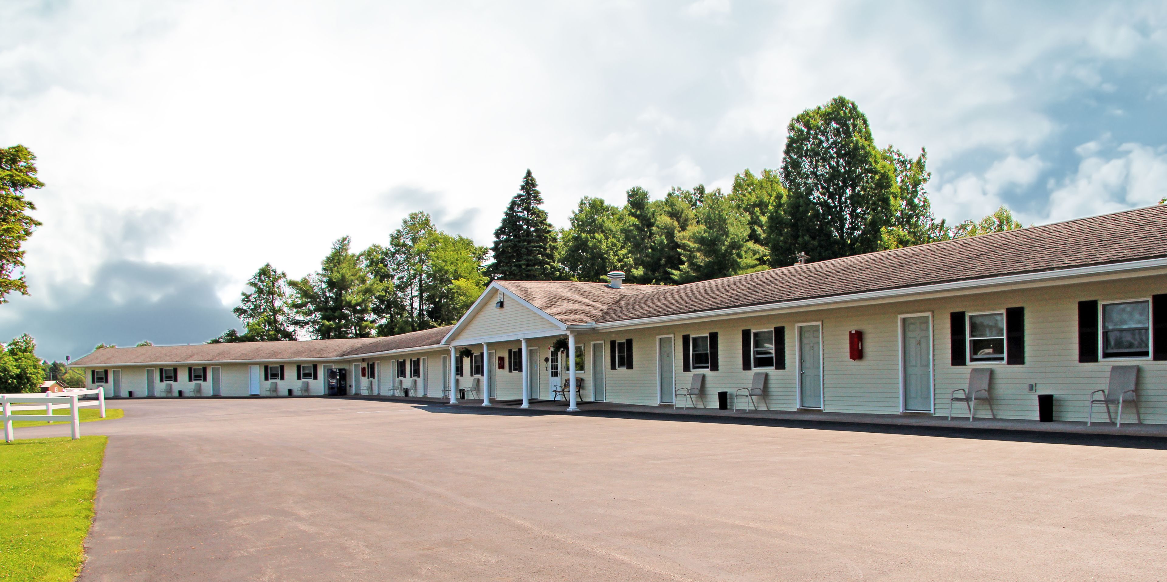 A row of motel buildings with a covered walkway and individual rooms.