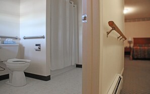 A hotel bathroom with a toilet, a towel rack, and a shower curtain. - Potsdam Inn (Potsdam)