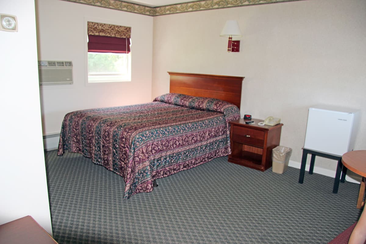 Une chambre d’hôtel avec un grand lit, une table de chevet, un bureau et une chaise.