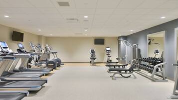 A gym with treadmills, weight machines, and dumbbells.