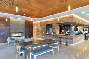Un interior moderno con techo de madera, zona de bar, asientos y chimenea.