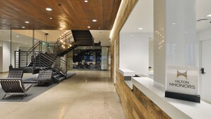 Eine moderne Hotelhalle mit Holzboden, einer Rezeption und einer Treppe.