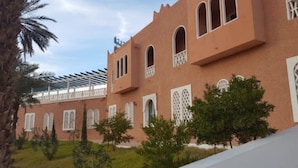 A building with arched windows and a covered walkway. - Hôtel Taghit Saoura (Taghit)