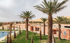 Alberca techada, alberca al aire libre y sombrillas en la alberca