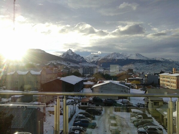 A snowy town with mountains in the background, a parking lot, and buildings with snow on their roofs. - Hotel Mil 810 (Ushuaia)