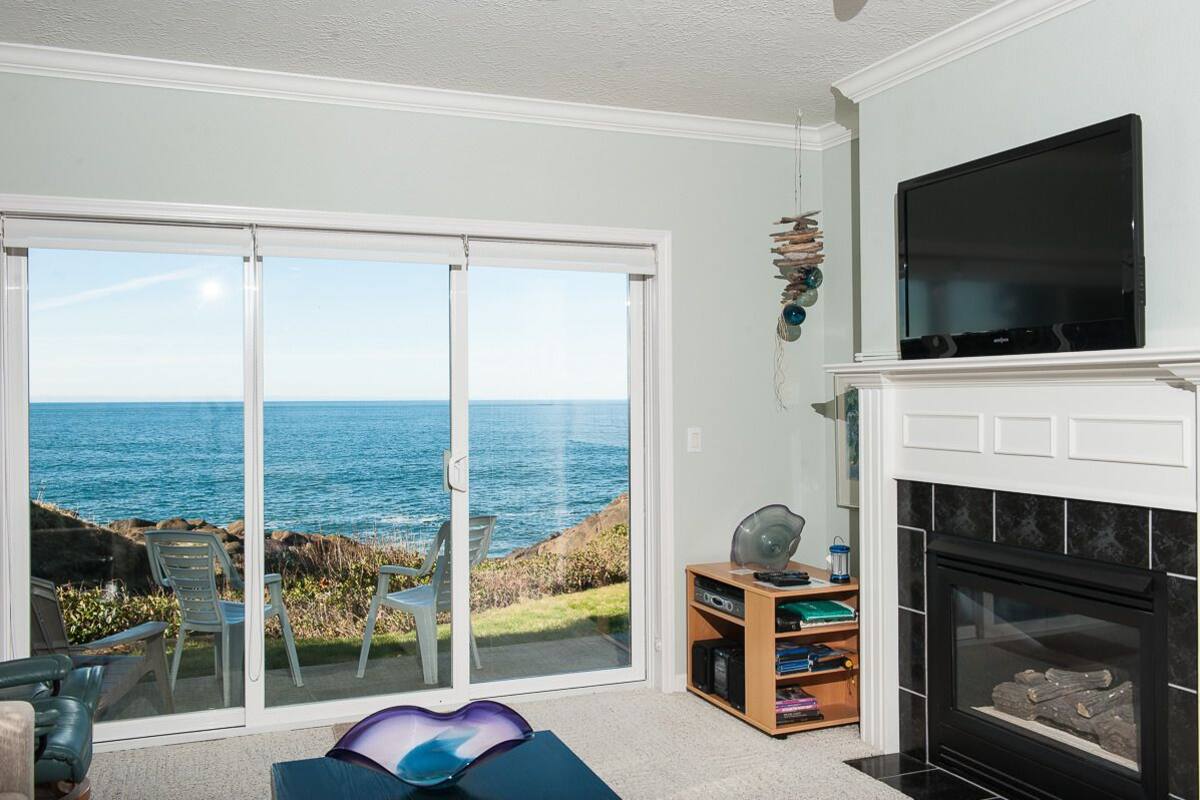 A living room with a large sliding glass door leading to a balcony with a view of the ocean.