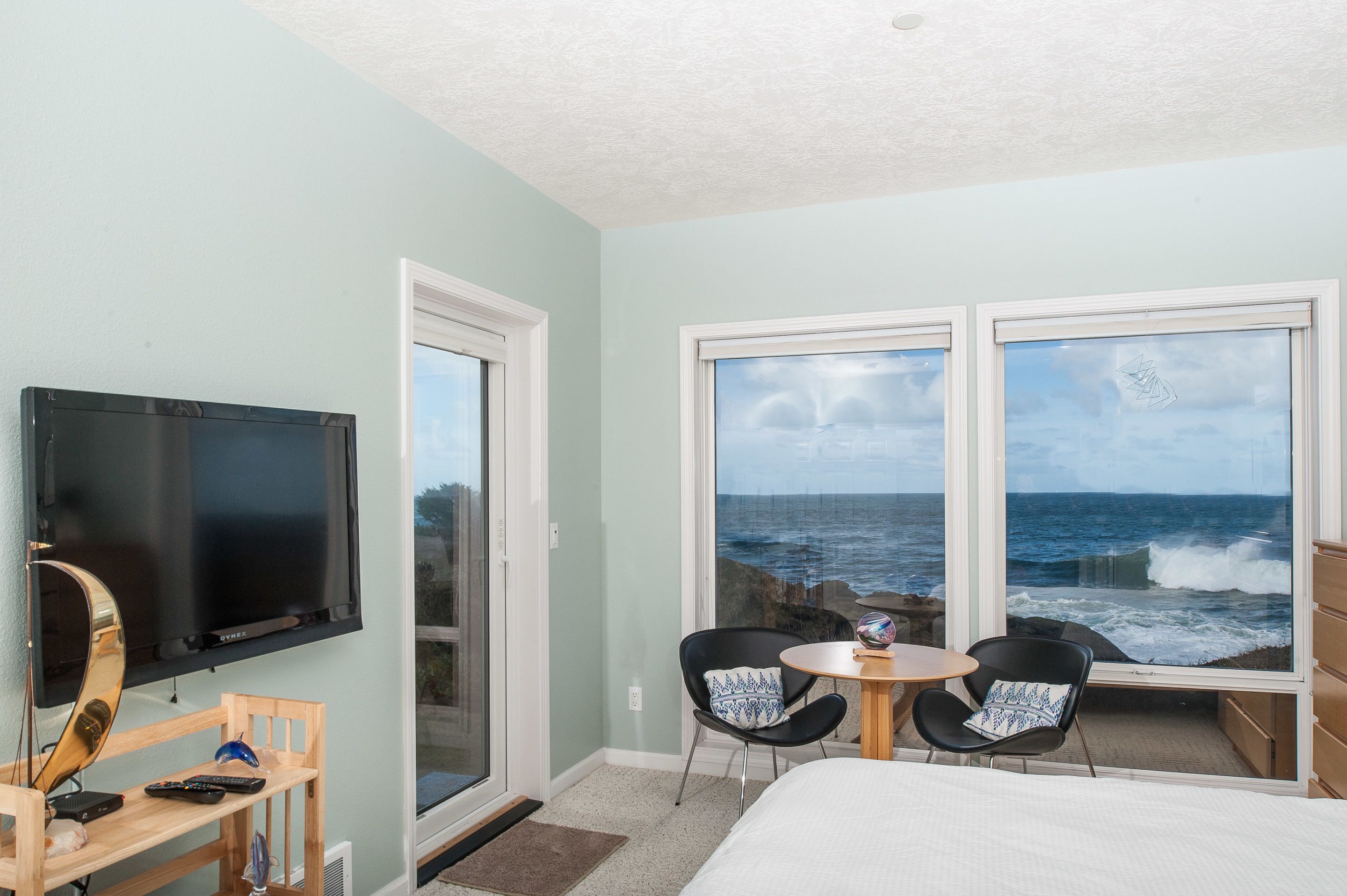 A room with a television, a small table, two chairs, and a bed.