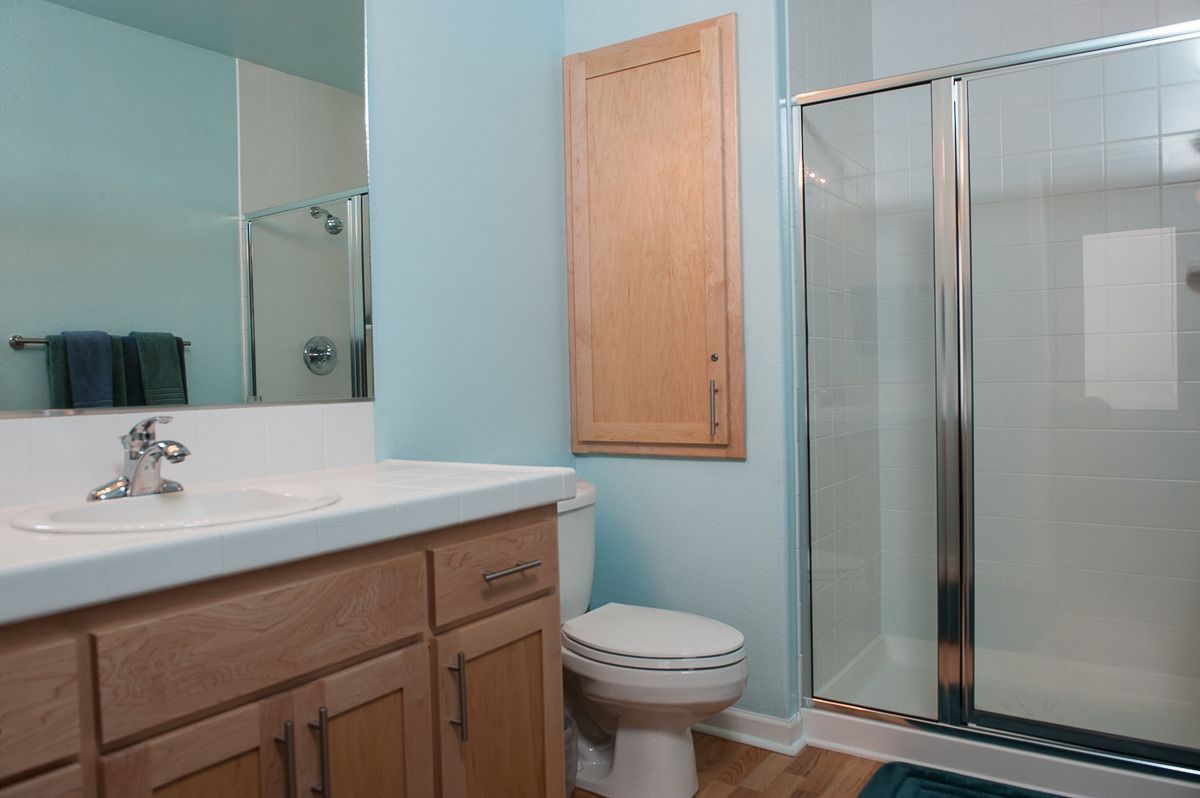 Een badkamer met douche, wastafel en toilet.