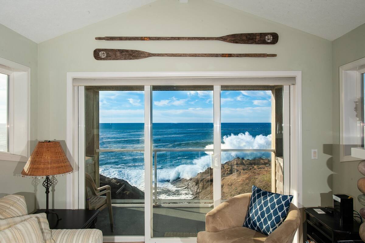 A room with a large sliding glass door leading to a view of the ocean.