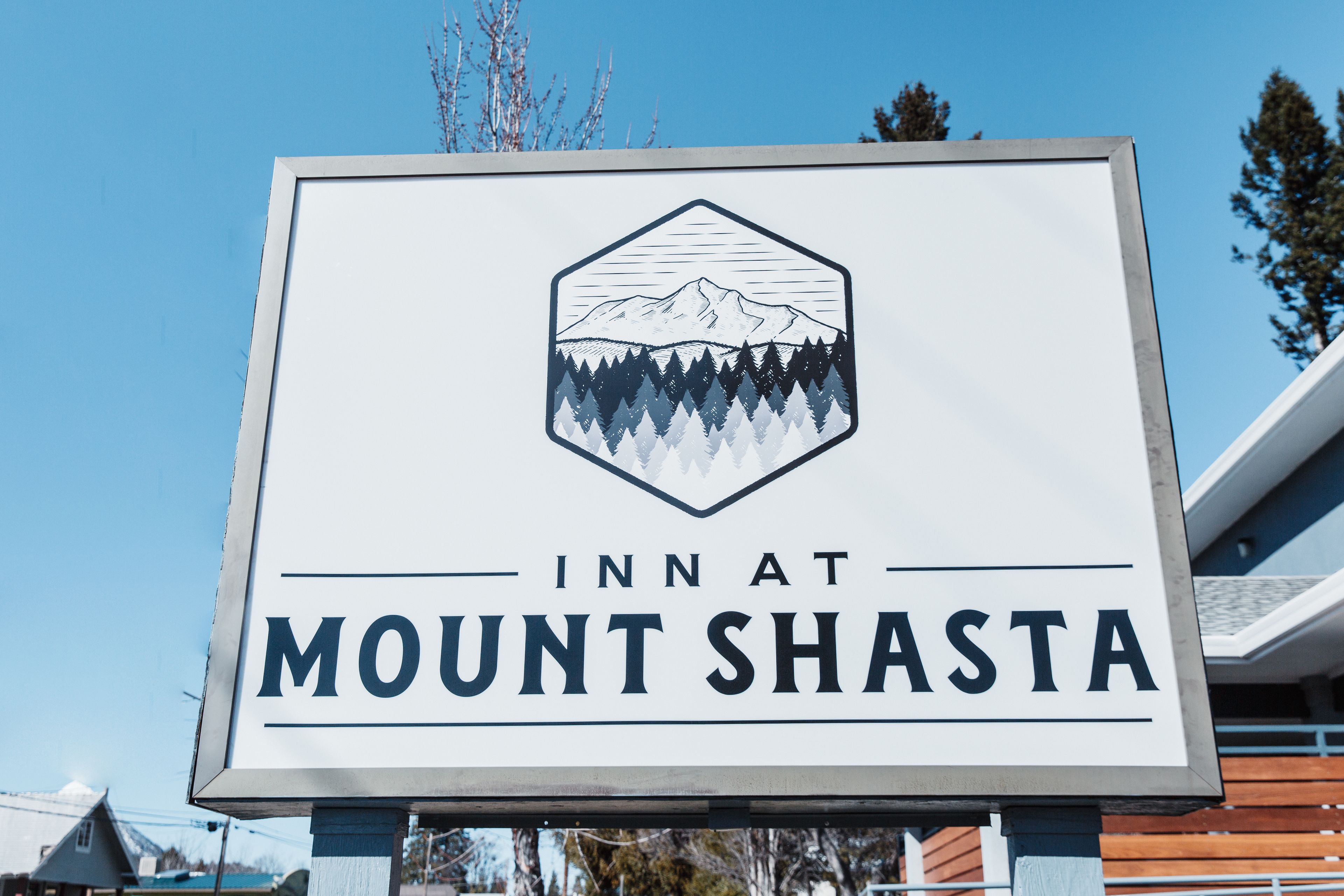 A sign for the Mount Shasta Inn, featuring a mountain and forest graphic.