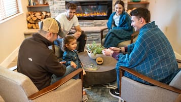 A cozy living room with a fireplace, comfortable seating, and a coffee table with a plant.
