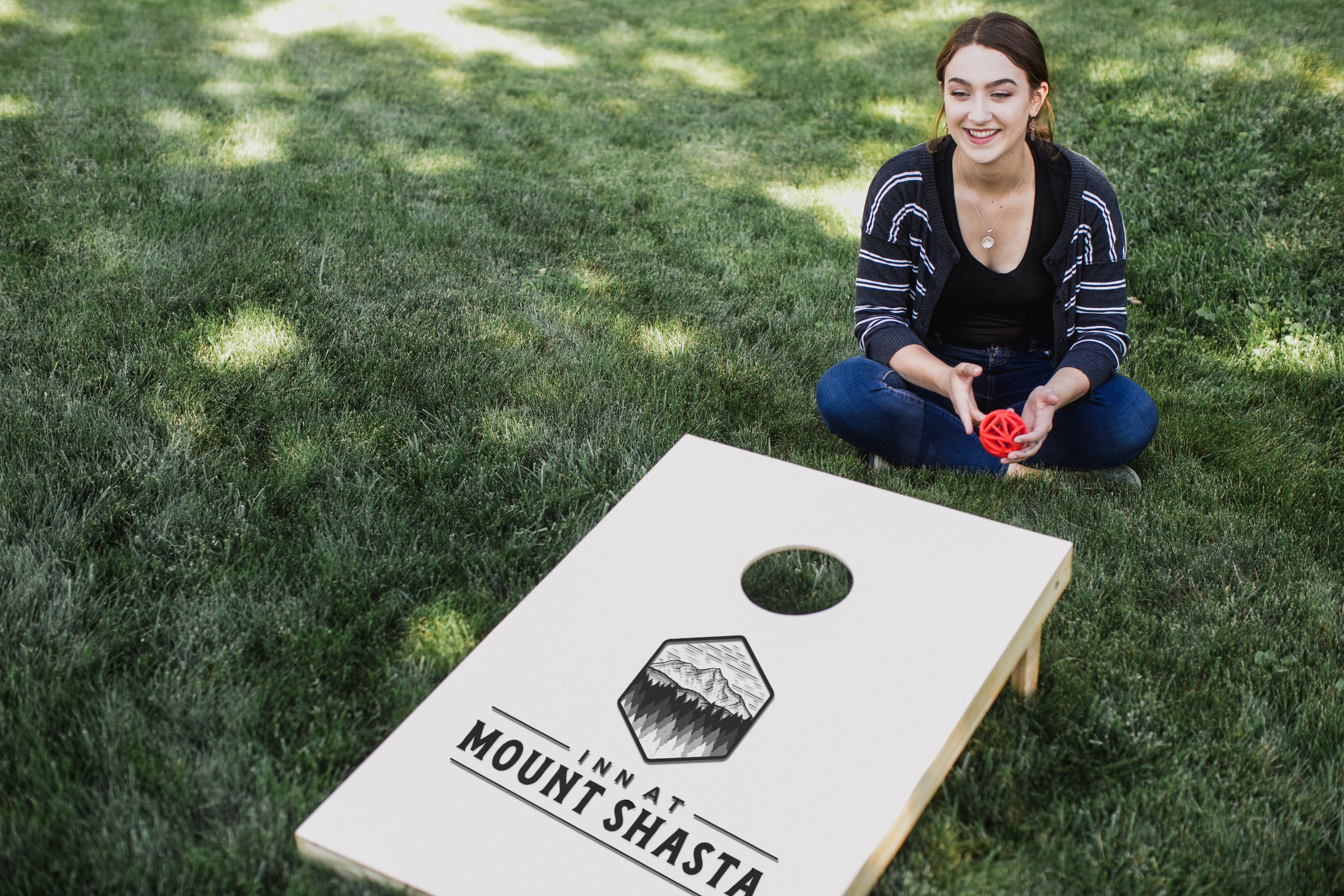 Une personne est assise sur l’herbe, devant une planche de bois sur laquelle on peut lire : « AUBERGE DU MONT SHASTA ».
