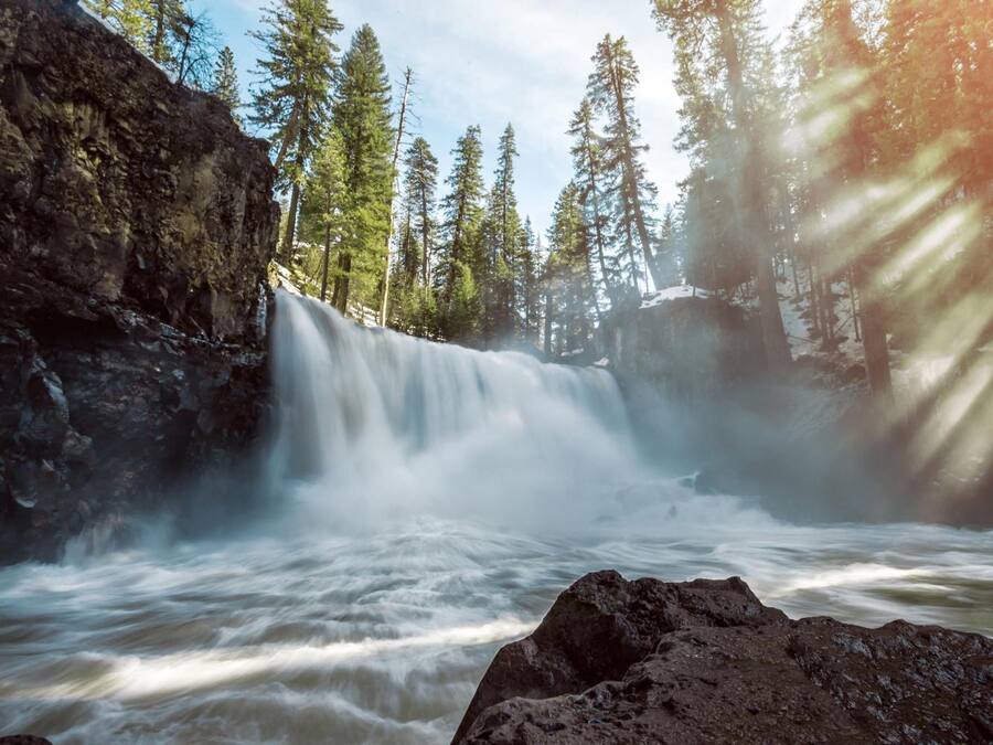 Une cascade entourée d’arbres et de rochers.