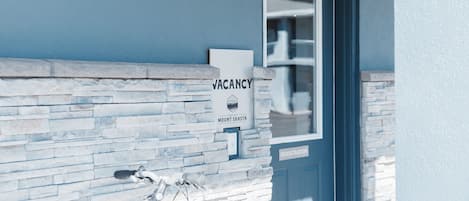 A building with a 'VACANCY' sign, a stone facade, and a registration door.
