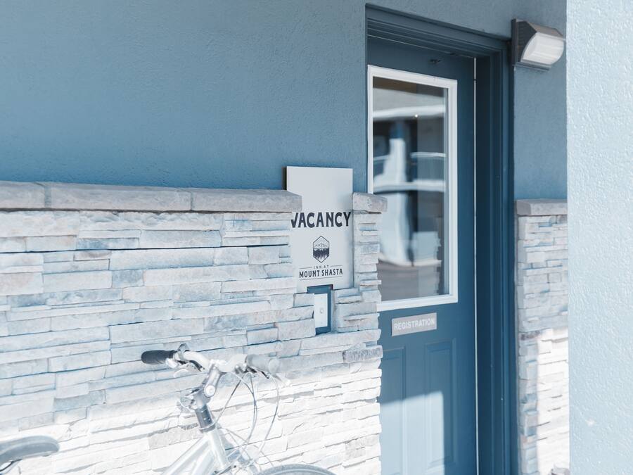 A building with a 'VACANCY' sign, a stone facade, and a registration door.