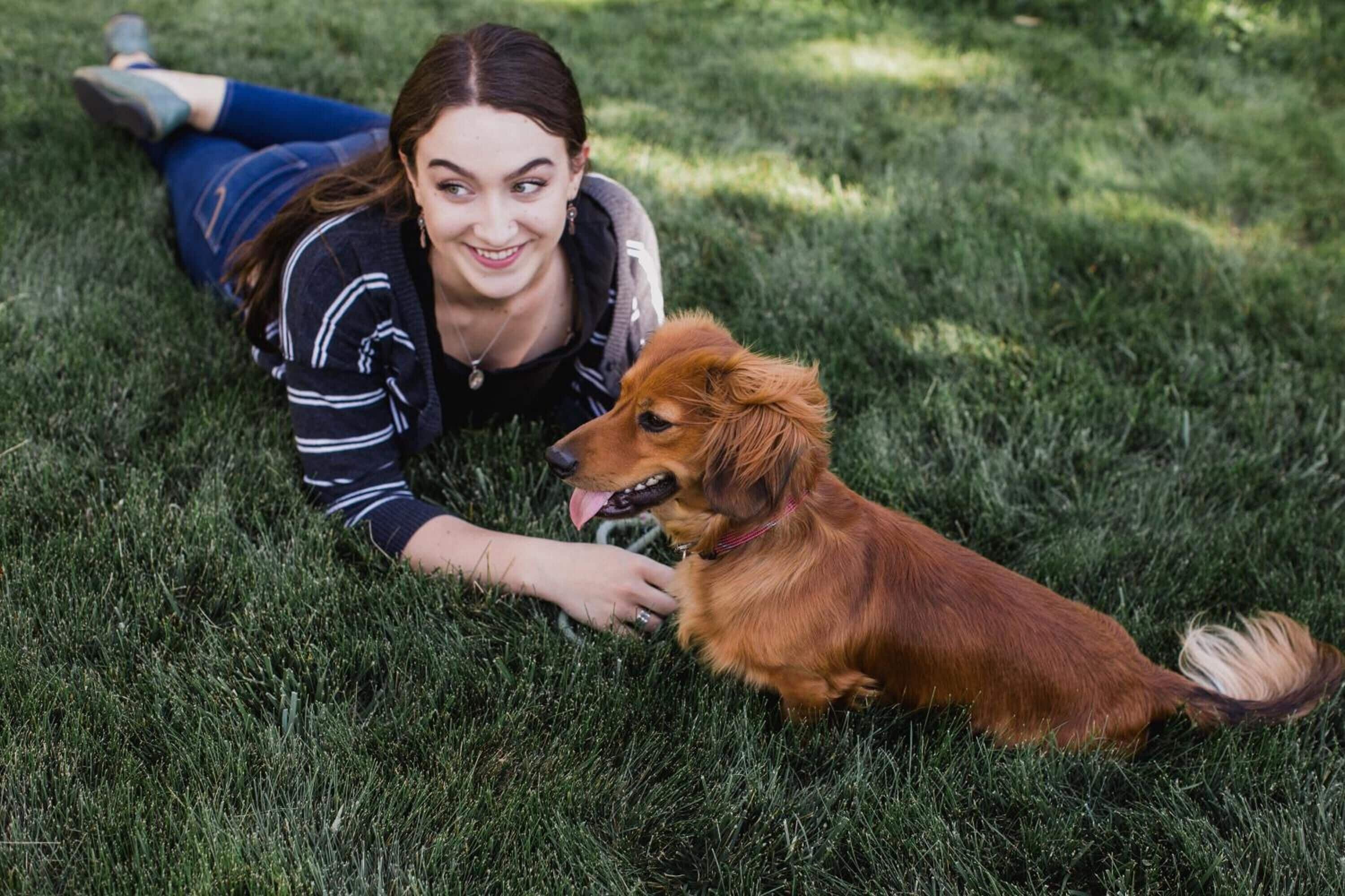 A person lying on grass with a dog.