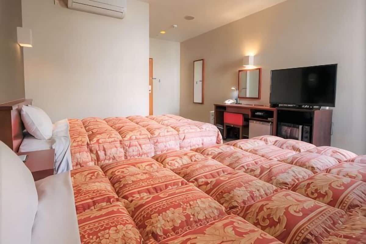 Ein Hotelzimmer mit einem großen Bett, einem Schreibtisch, einem Sessel, einem Fernseher und einem Spiegel.