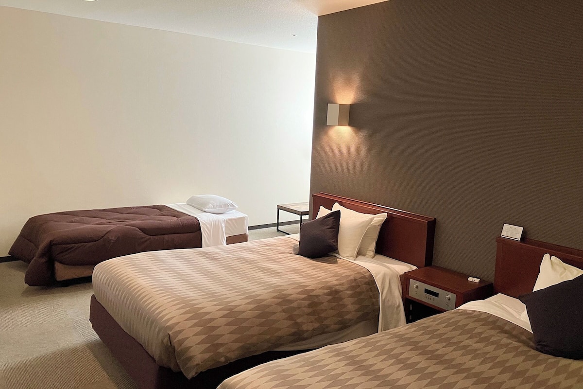 Ein Hotelzimmer mit zwei Betten, einem Nachttisch und einer Wandleuchte.