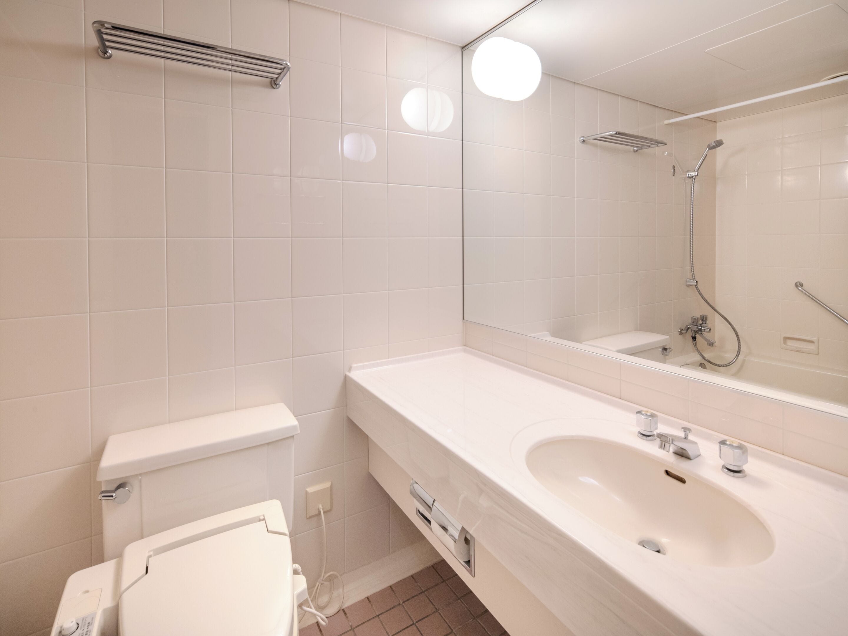 Un baño moderno con lavamanos, inodoro y ducha blancos.