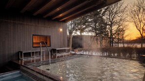 A spa area with a hot tub, wooden walls, and a view of trees and a sunset. - TATESHINA LAKE RESORT (Tateshina)