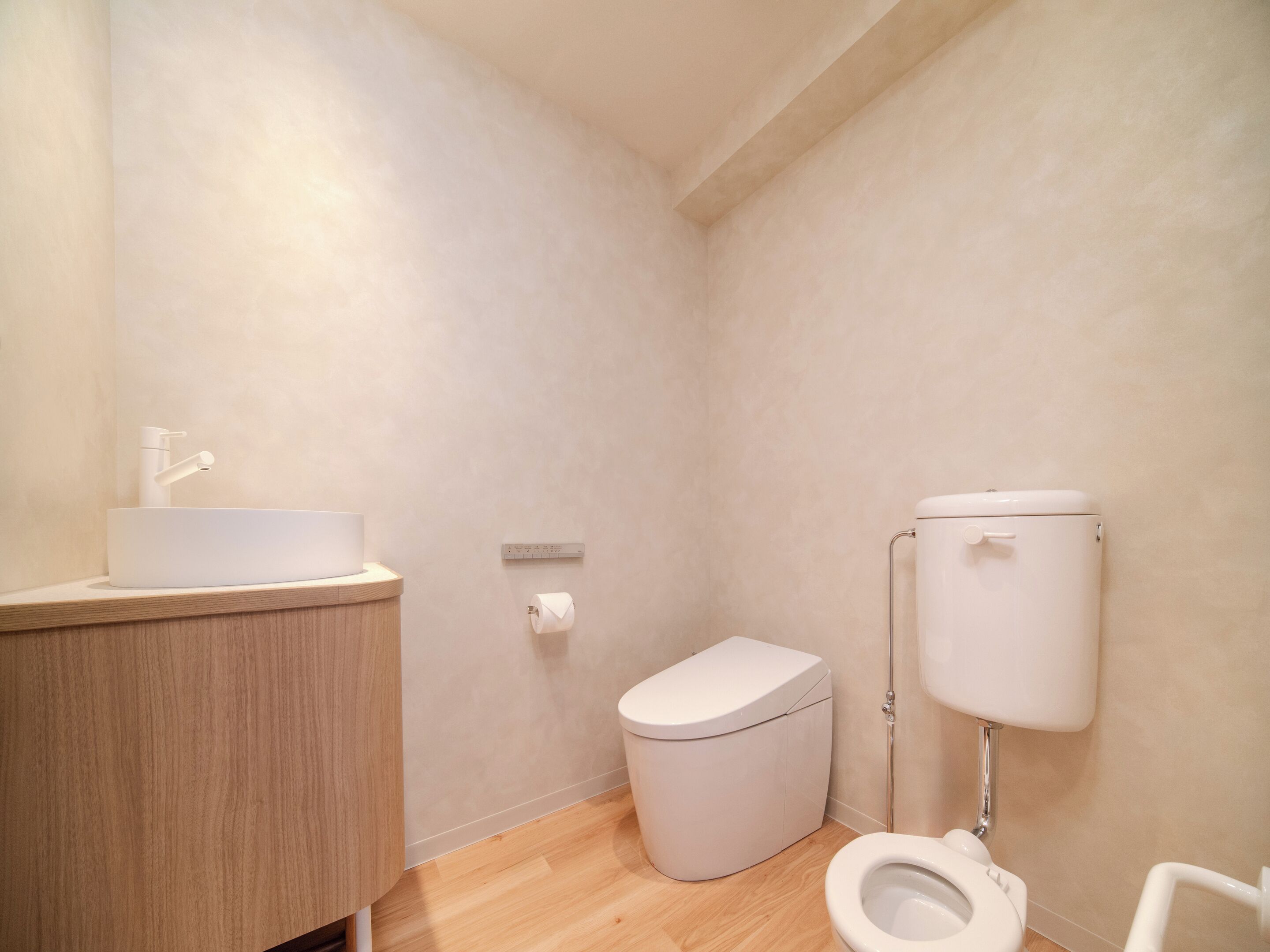Um banheiro pequeno com vaso sanitário, pia e suporte para papel higiênico.