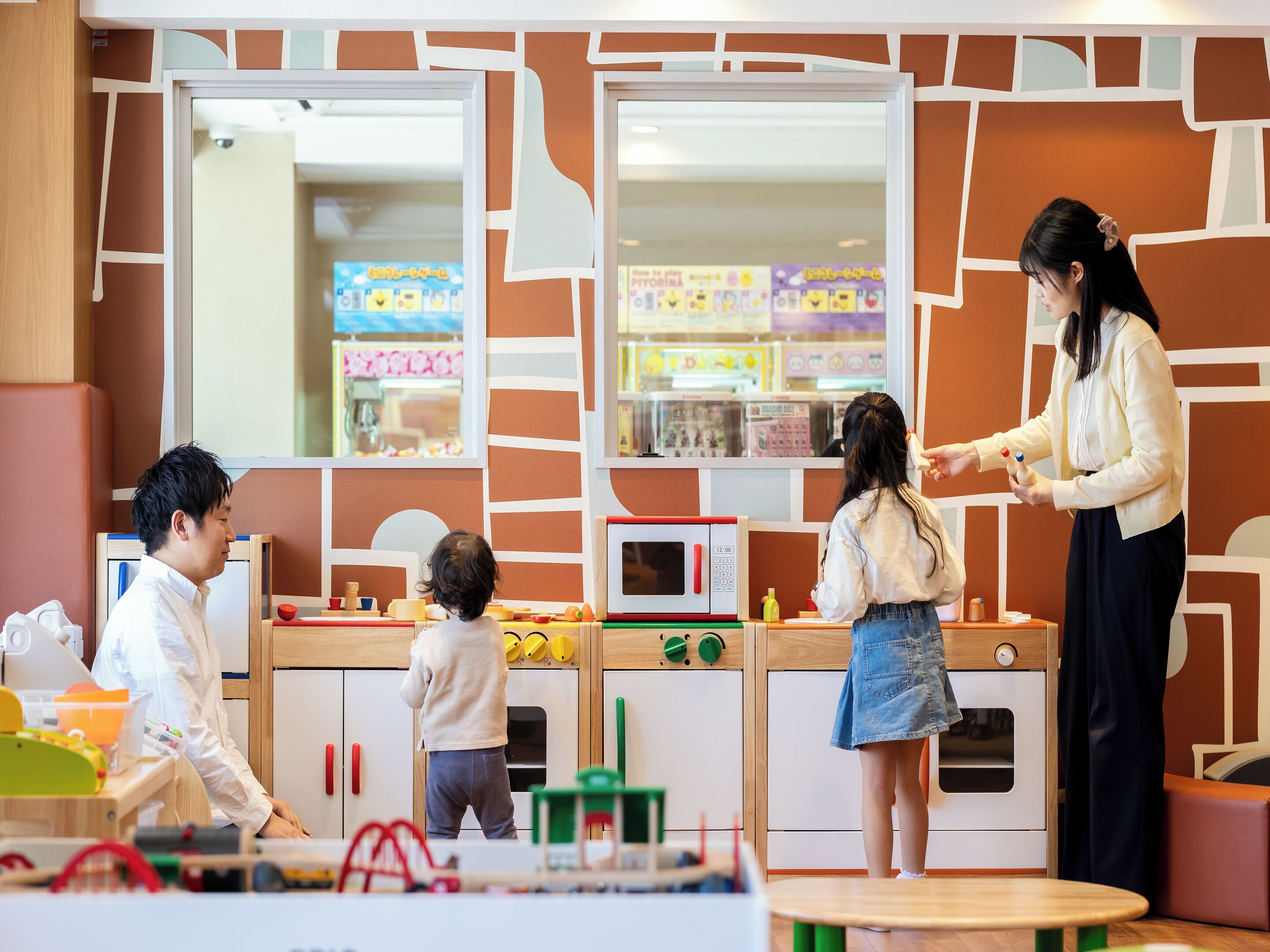 A play kitchen with a microwave, oven, and various kitchen utensils.