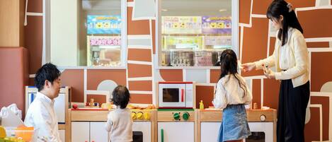 A play kitchen with a microwave, oven, and various kitchen utensils.