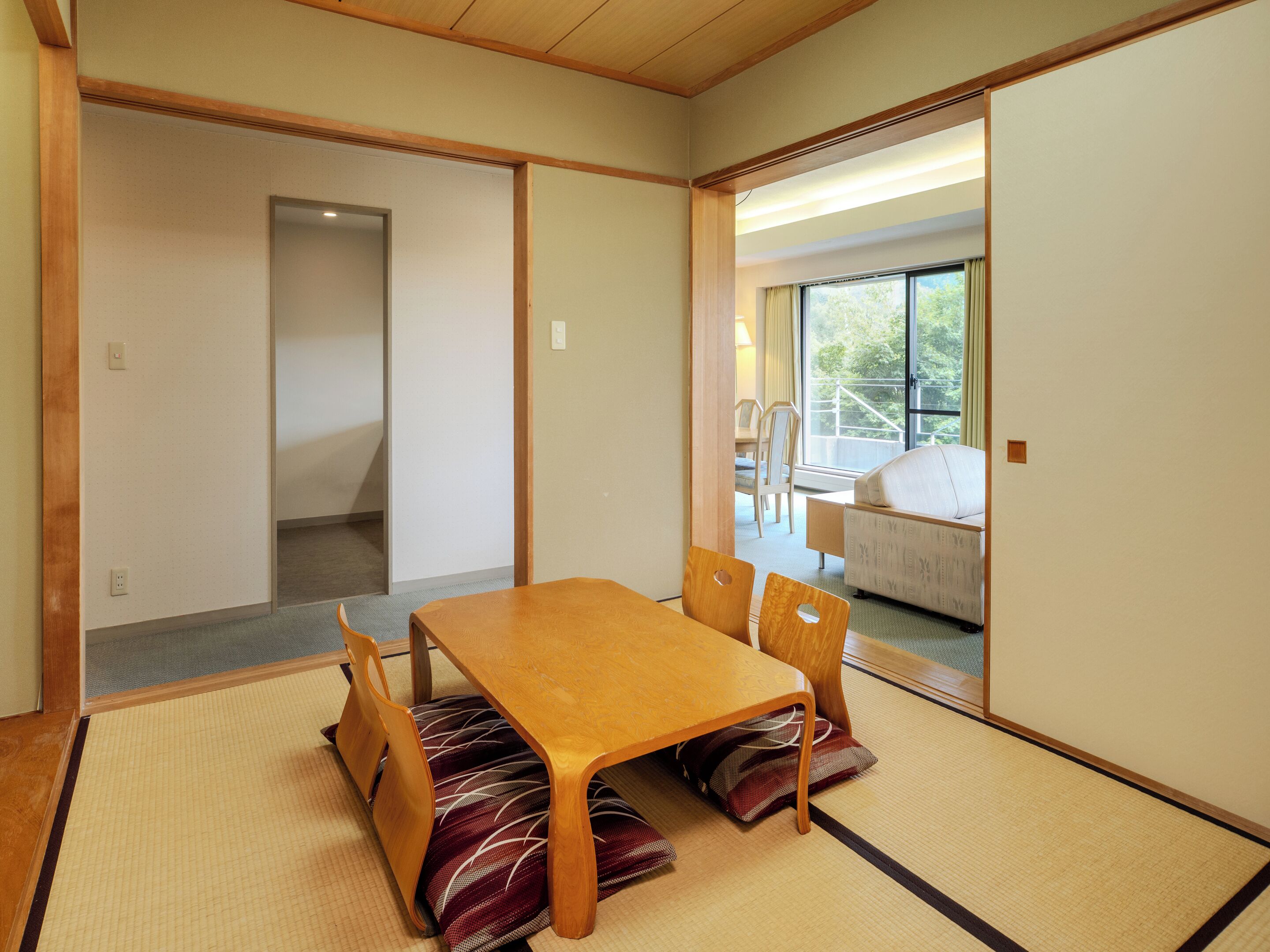 A traditional Japanese-style room with tatami flooring, a wooden table, and a sofa.