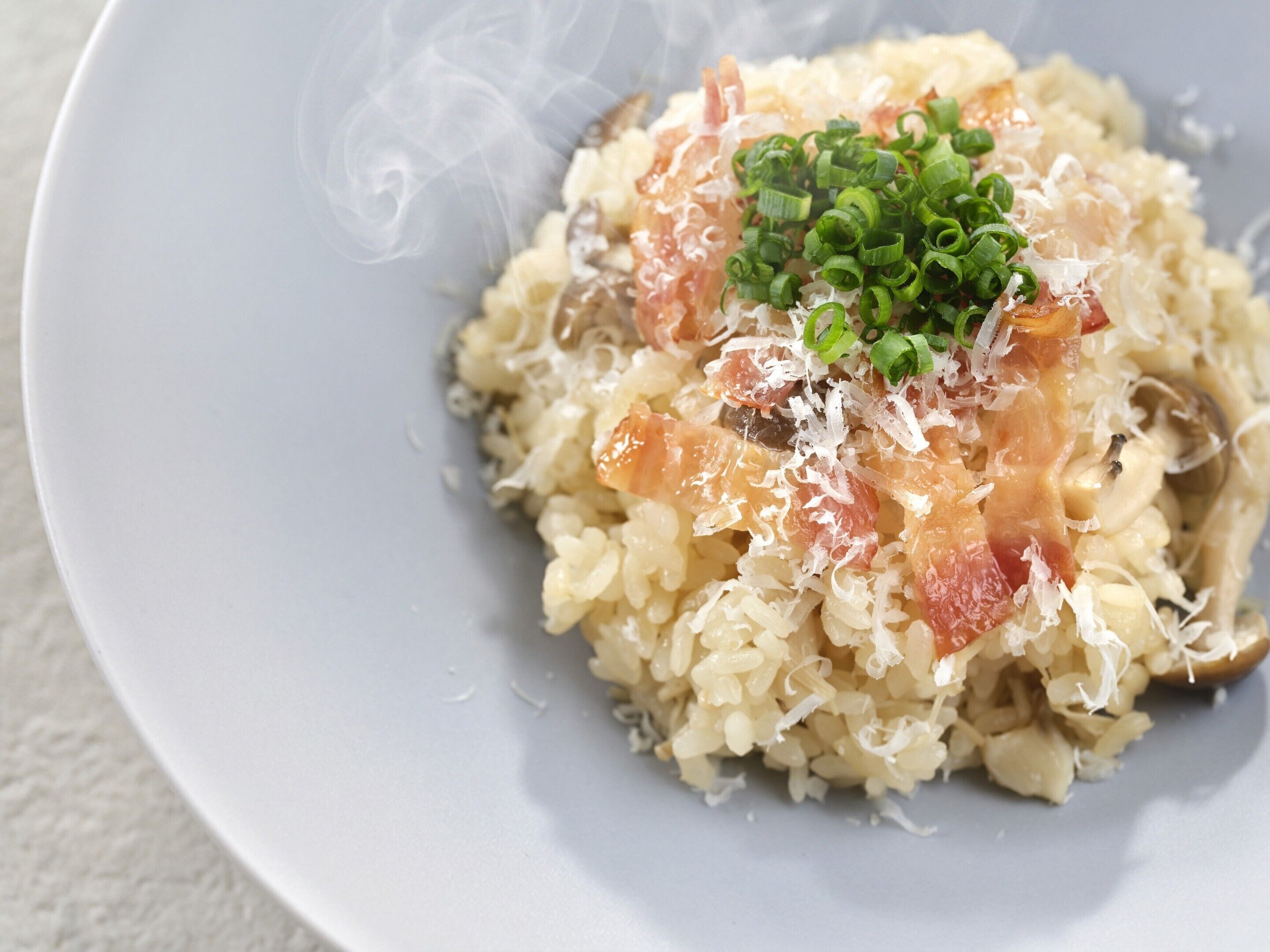 Un plato de comida con arroz, salmón y cebollas verdes.